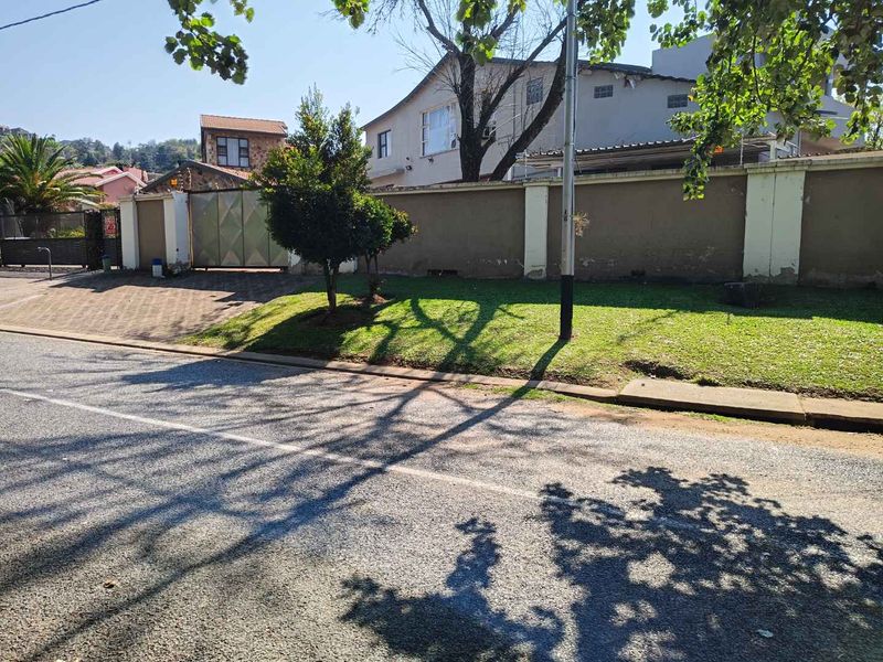 Street view of the property showing the perimeter wall, paved driveway entrance, and metal gate access.