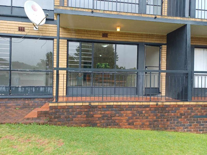 Ground floor patio area featuring brick facade, metal balustrades, and sliding glass door access to the apartment interior.