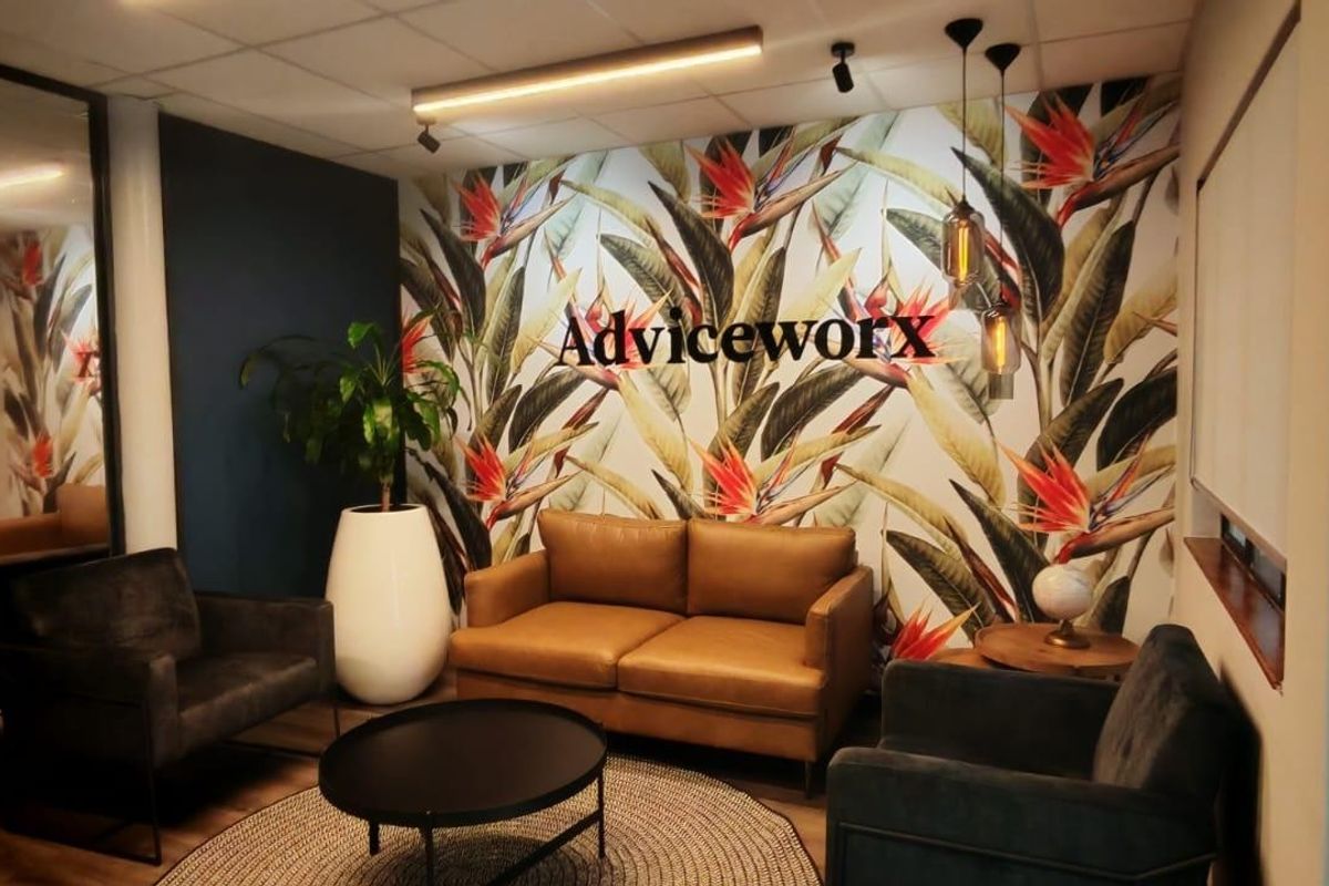 A modern, well-appointed office reception or waiting area featuring a striking botanical feature wall, drop ceiling, and contemporary lighting fixtures.