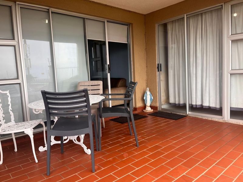 A covered balcony featuring terracotta tile flooring and large sliding glass doors providing access to the interior living spaces.