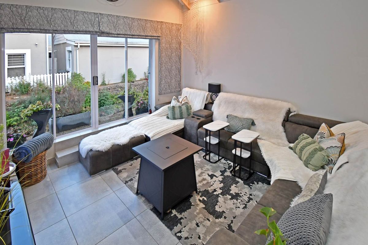 A bright living room featuring large sliding glass doors that provide access to the garden and ample natural light.