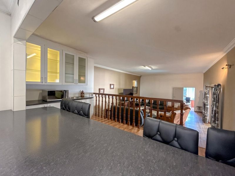 Open plan living area featuring a kitchen nook with built-in cabinetry and a wooden balustrade overlooking the lower lounge space.