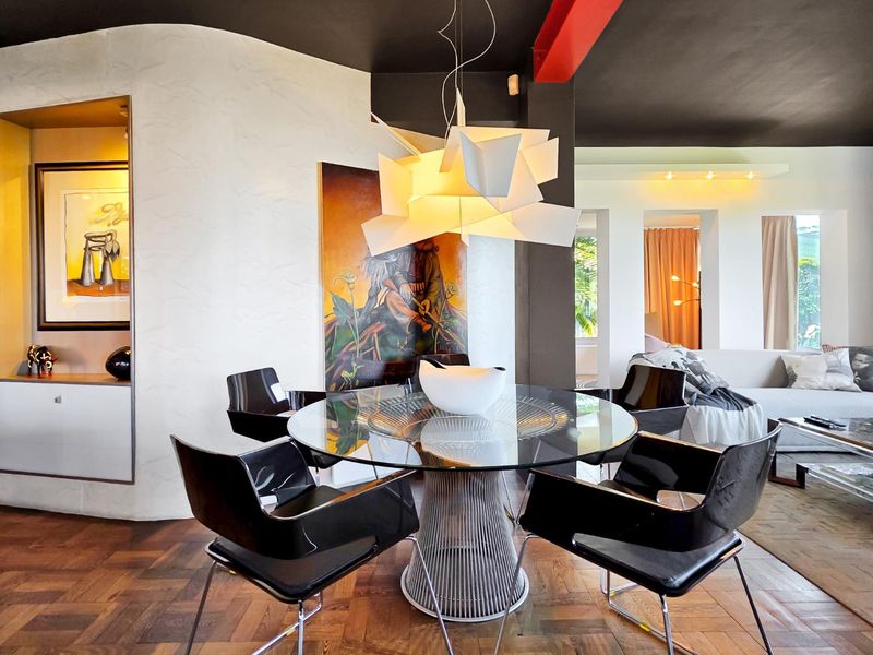 A modern open-plan living and dining area featuring rich parquet flooring, a striking black ceiling with exposed structural elements, and a built-in display niche.