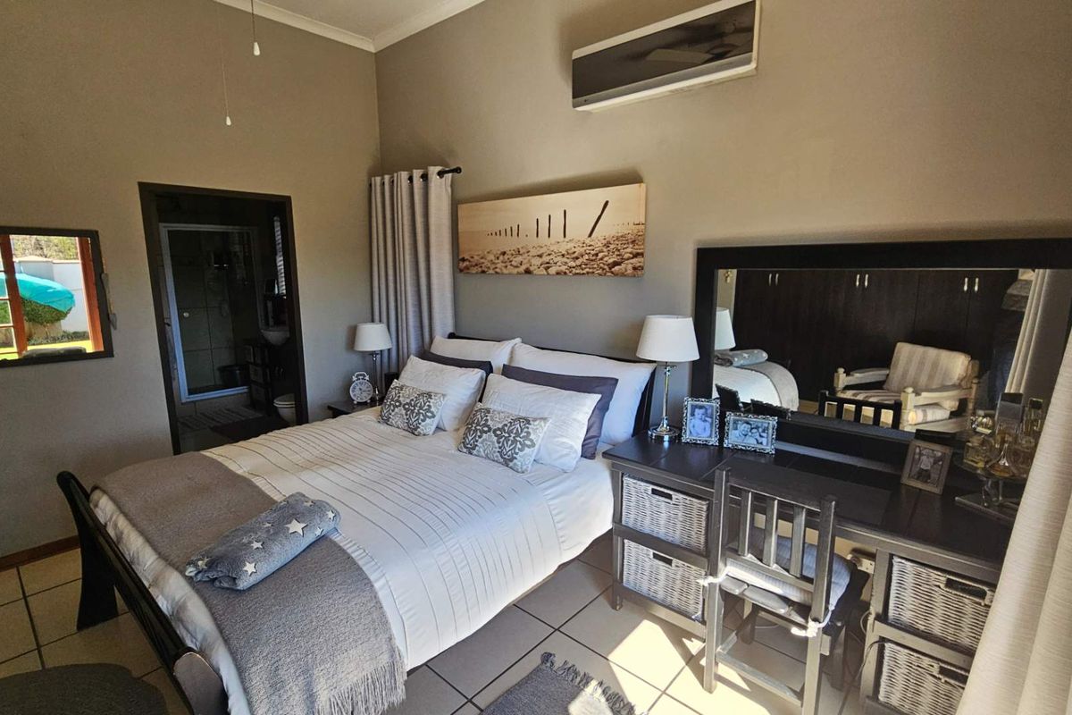 A well-maintained bedroom featuring tiled flooring, a wall-mounted air conditioning unit, and an en-suite bathroom access.