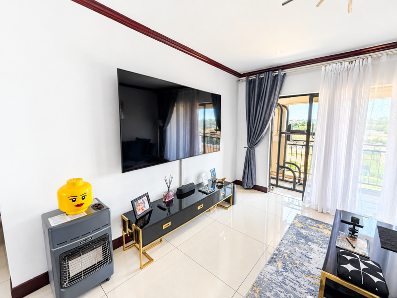 A bright living room featuring polished tile flooring, crown molding, and a large sliding glass door providing access to a balcony.