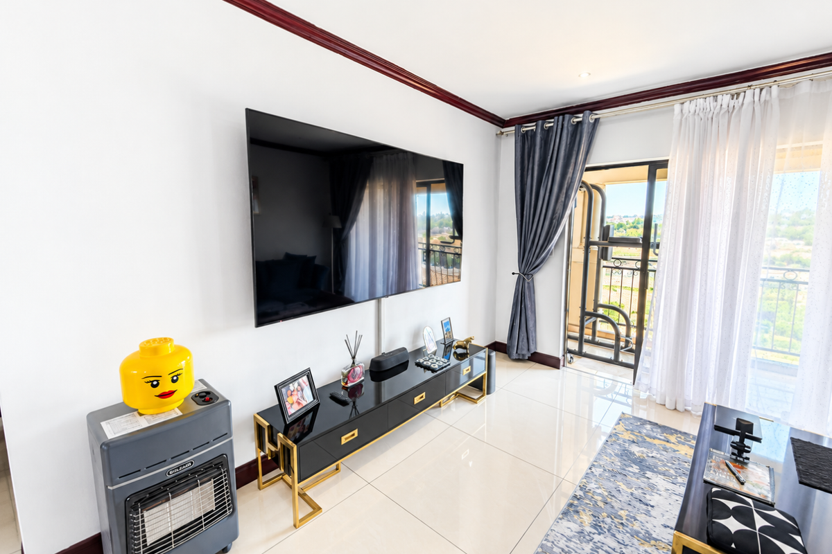 A bright living room featuring polished tile flooring, crown molding, and a large sliding glass door providing access to a balcony.