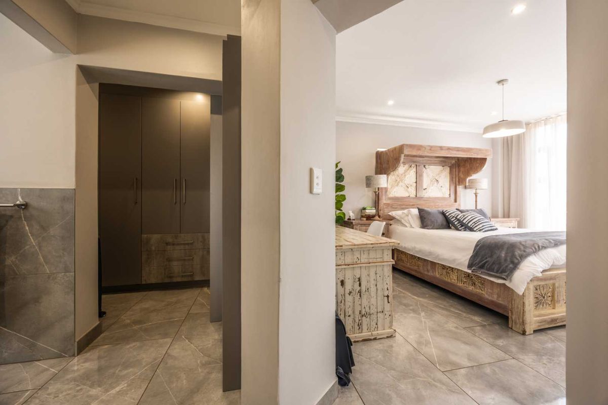 A well-maintained bedroom featuring large format floor tiles, built-in cabinetry, and recessed ceiling lighting, creating a clean and modern living space.
