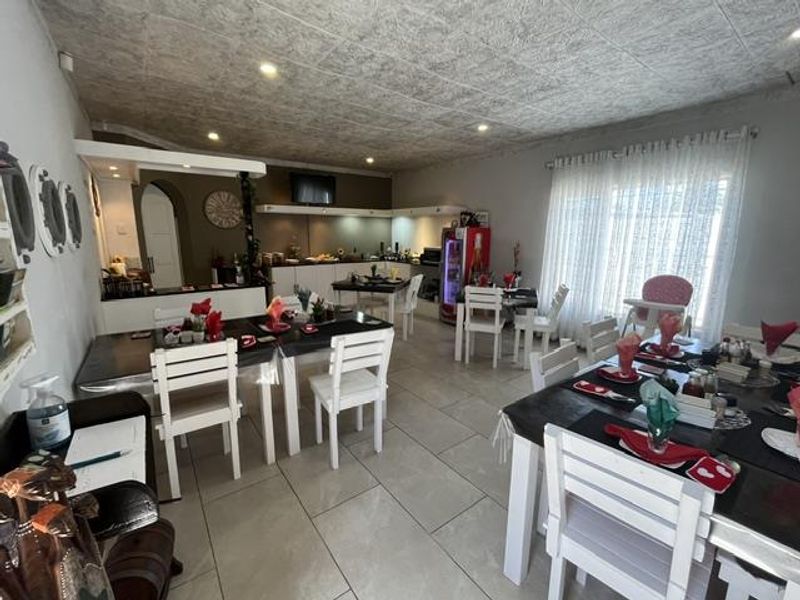 Spacious open-plan dining and kitchen area featuring tiled flooring, recessed lighting, and a textured ceiling, suitable for large gatherings or commercial use.