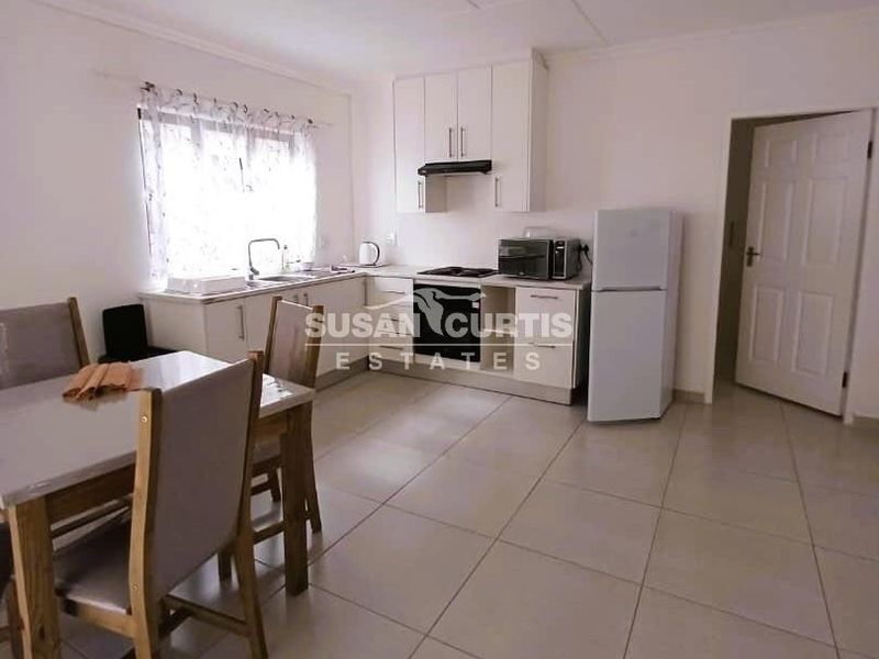 Open-plan kitchen and dining area featuring tiled flooring, built-in cabinetry, and integrated cooking appliances.