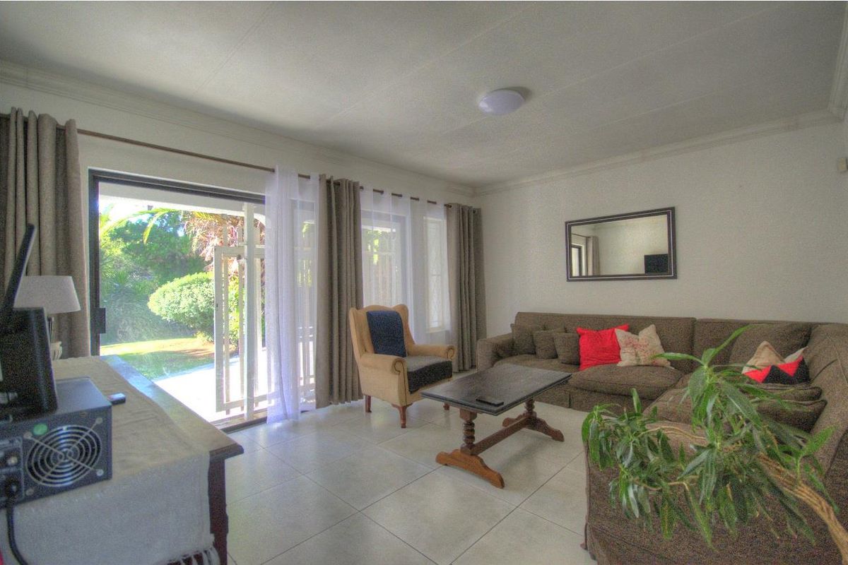A bright living room featuring large sliding glass doors that provide direct access to the garden and patio area.