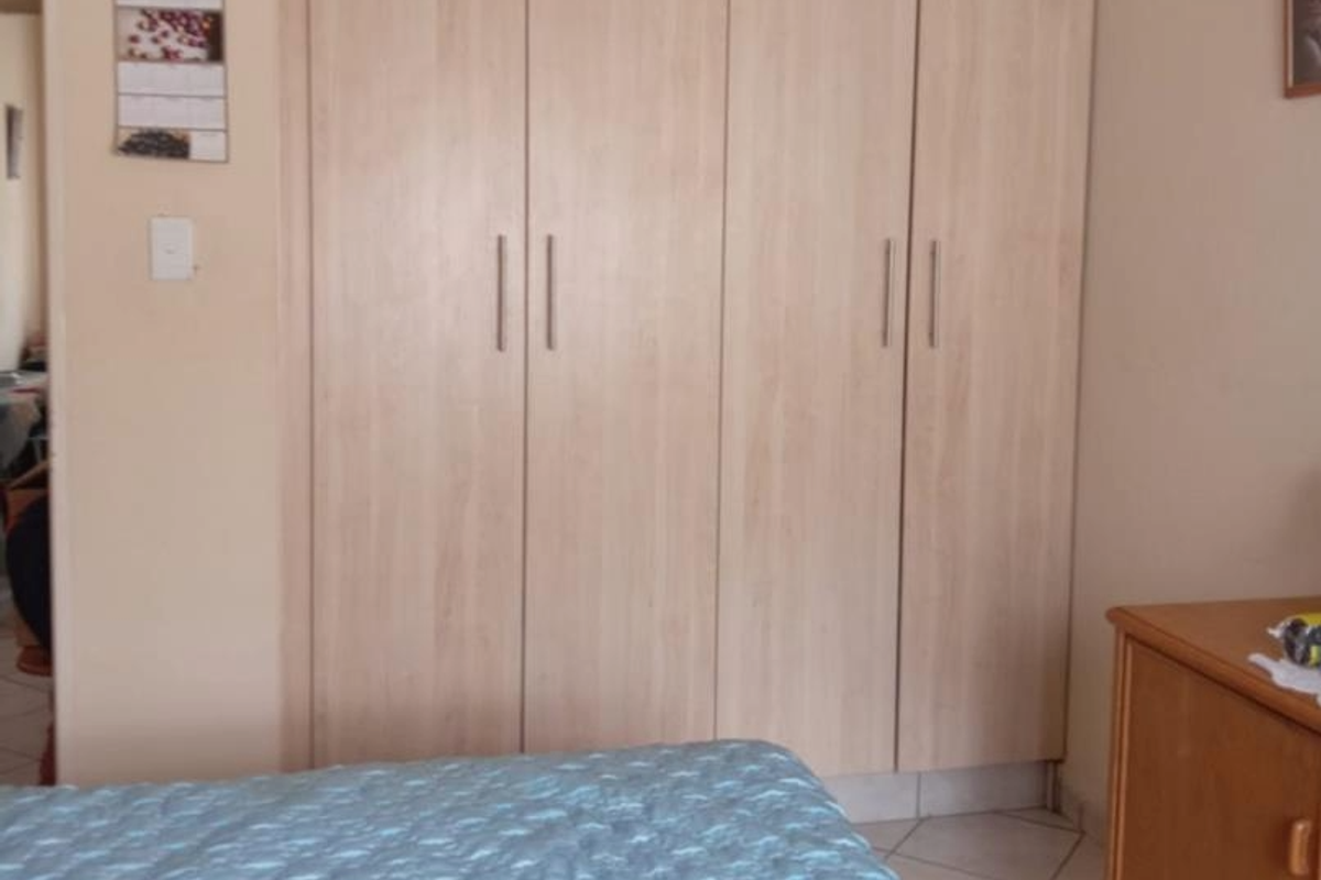 A bedroom featuring built-in wooden cabinetry with modern handles and tiled flooring.