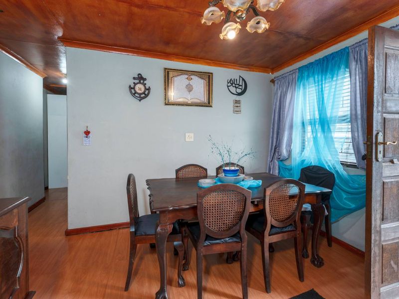 A dining room featuring laminate flooring, a timber ceiling, and a solid timber door, offering a traditional aesthetic with potential for modern updates.