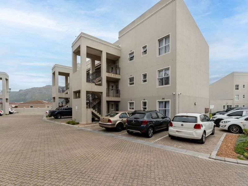 Exterior view of a multi-story apartment complex featuring paved parking areas and external staircases providing access to units.