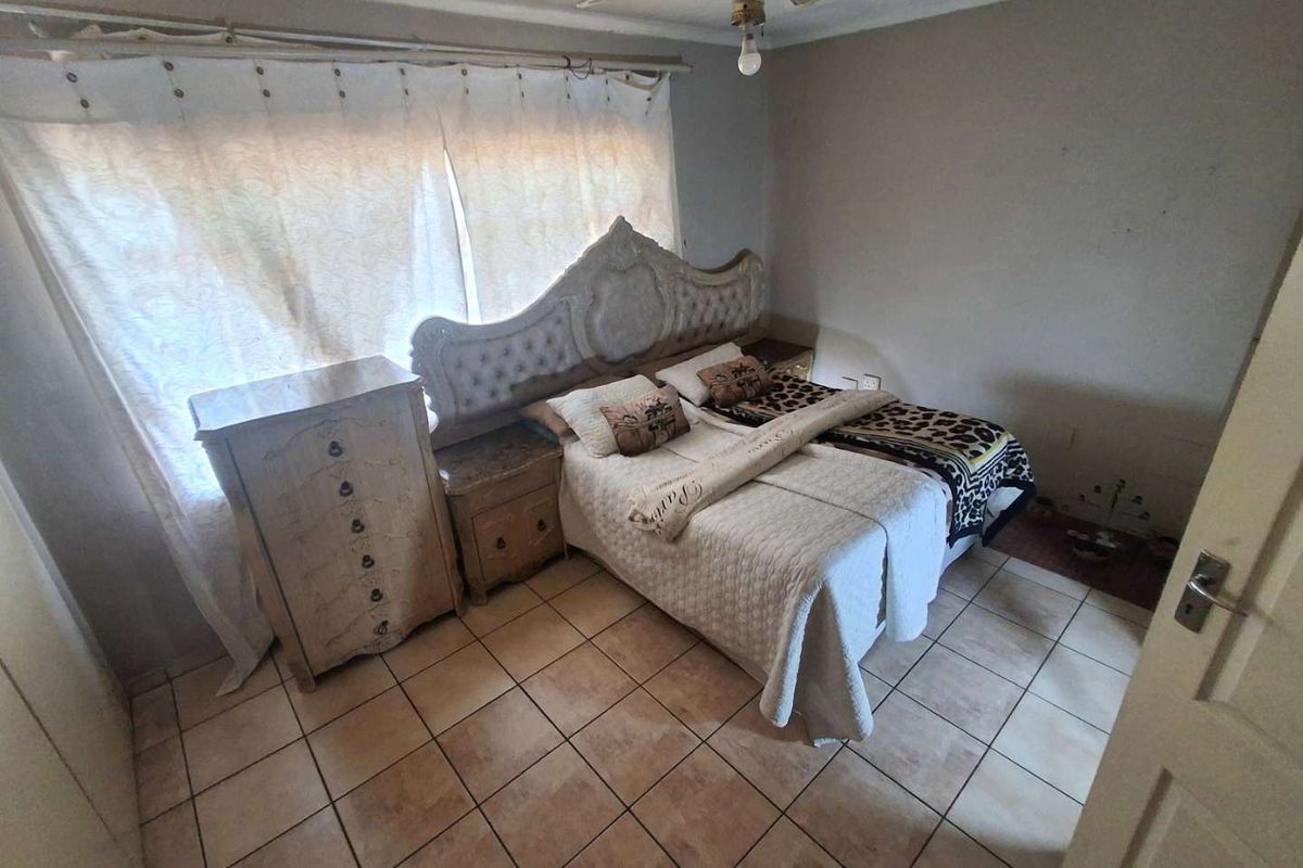 A bedroom featuring tiled flooring and a ceiling fan, requiring cosmetic updates to the wall finishes to improve the overall aesthetic.