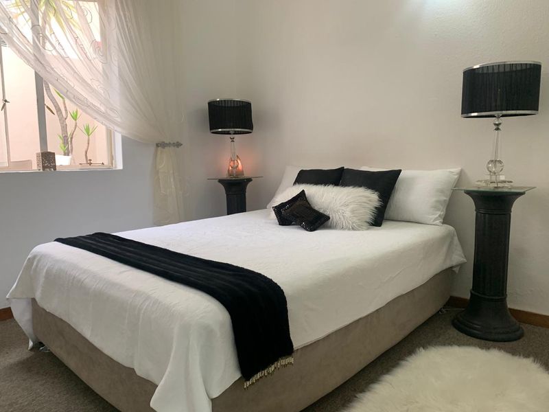 A well-maintained bedroom featuring neutral walls, carpeted flooring, and a window providing natural light.