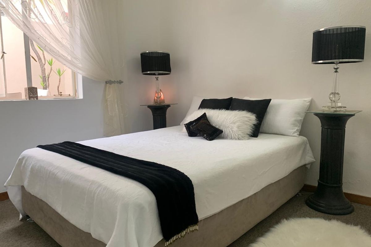 A well-maintained bedroom featuring neutral walls, carpeted flooring, and a window providing natural light.