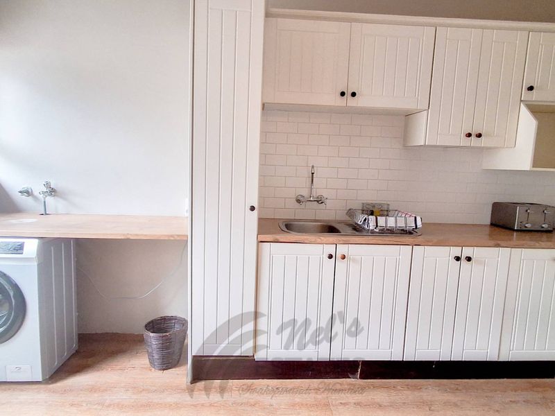 A functional laundry area featuring white built-in cabinetry, a wooden countertop, subway tile backsplash, and dedicated plumbing for a washing machine.