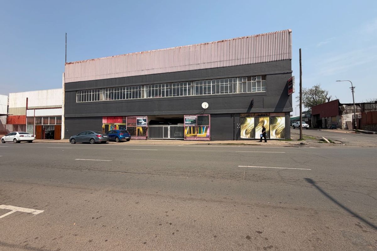Street-facing view of a commercial mixed-use building featuring large storefront windows, security access, and a prominent upper-level facade.