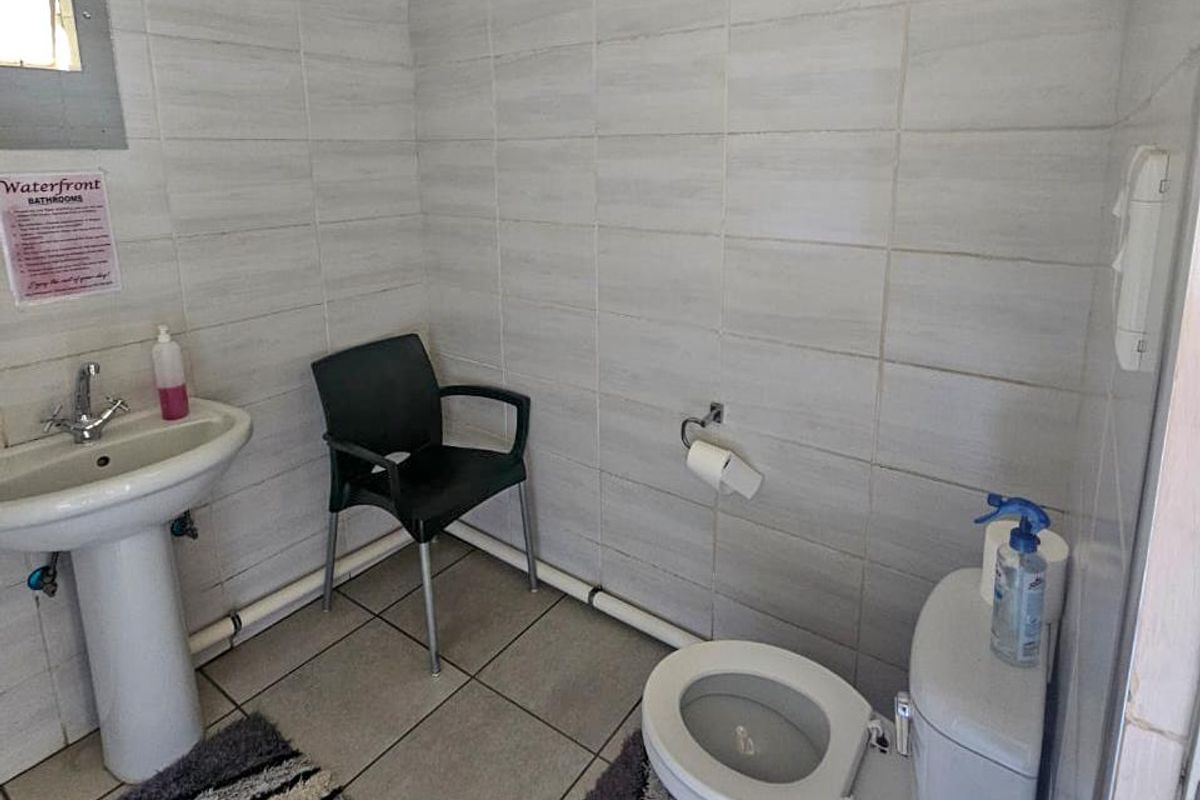 A functional bathroom featuring a pedestal basin, standard toilet, and full-height wall tiling.