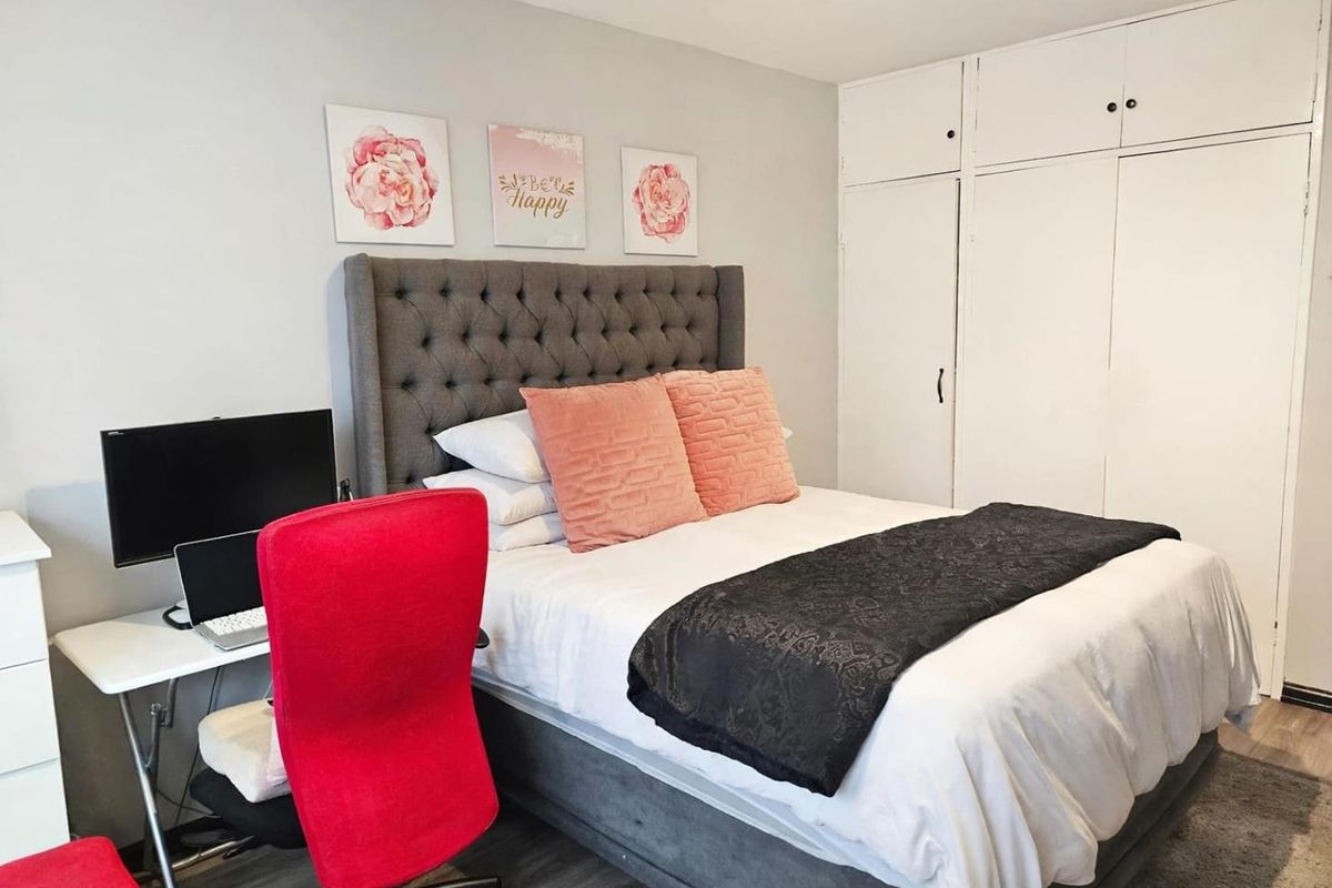 A bedroom featuring built-in white cupboards and wood-look flooring, providing a functional space with integrated storage solutions.