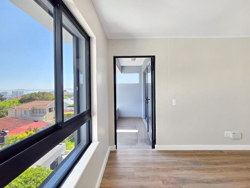 Bright and modern living area featuring laminate flooring, large windows with scenic views, and direct access to a private balcony.