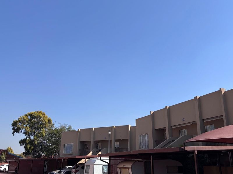 Exterior view of an apartment complex featuring covered parking bays and external staircases leading to upper-level units.