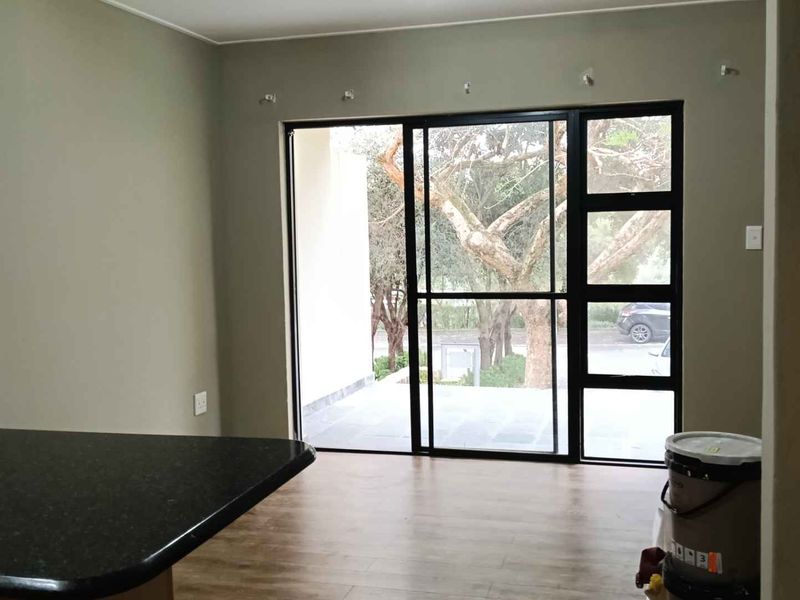 Open plan living area featuring laminate flooring, a granite breakfast bar, and large sliding glass doors leading to an outdoor patio space.