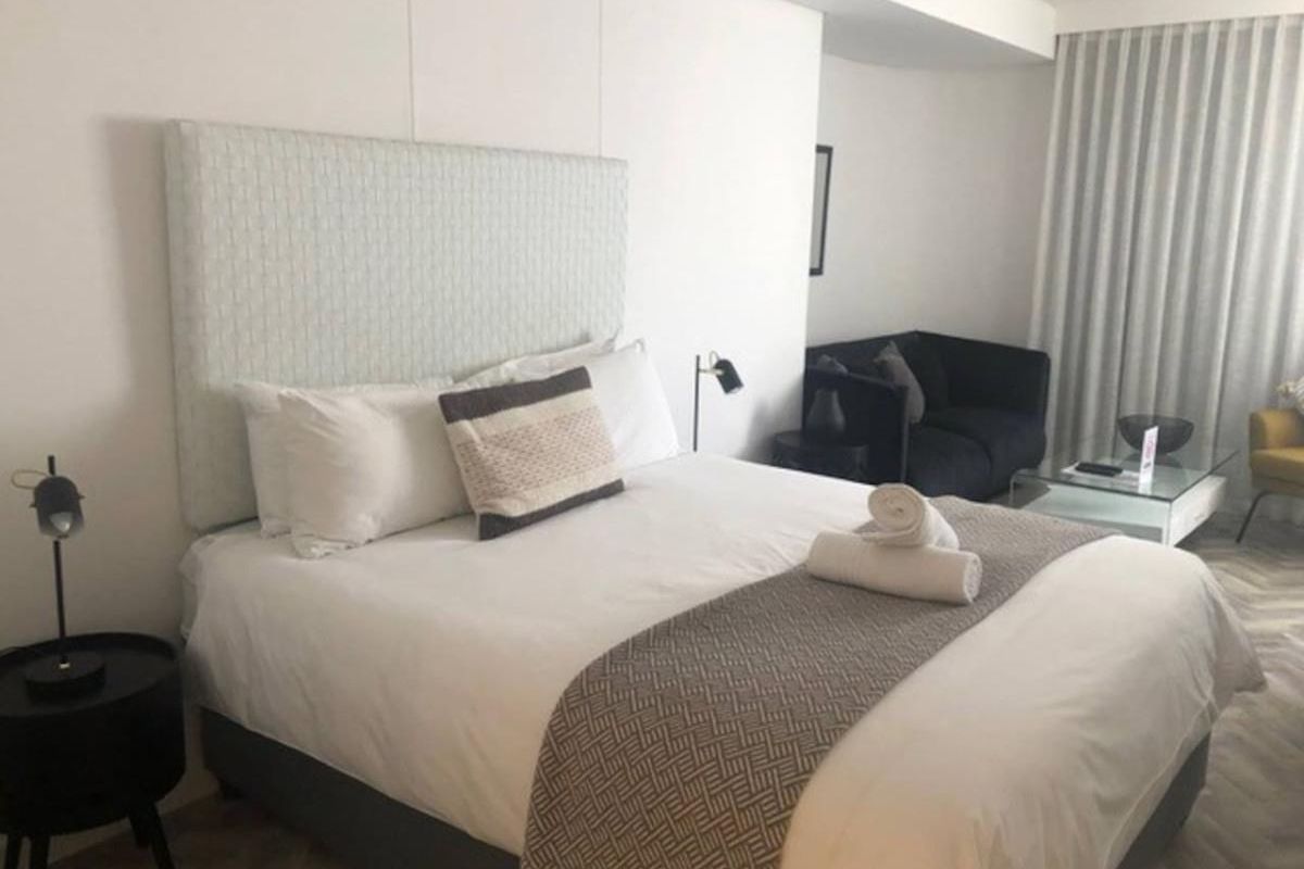 A well-maintained bedroom featuring herringbone flooring and a modern recessed curtain track, offering a clean and comfortable living space.