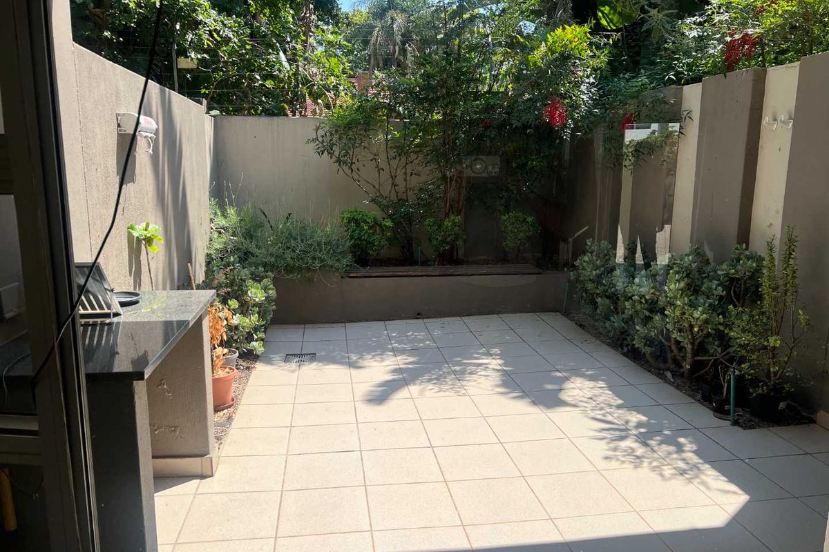 A private, paved patio area featuring a built-in granite countertop and a raised garden bed, perfect for outdoor entertaining.