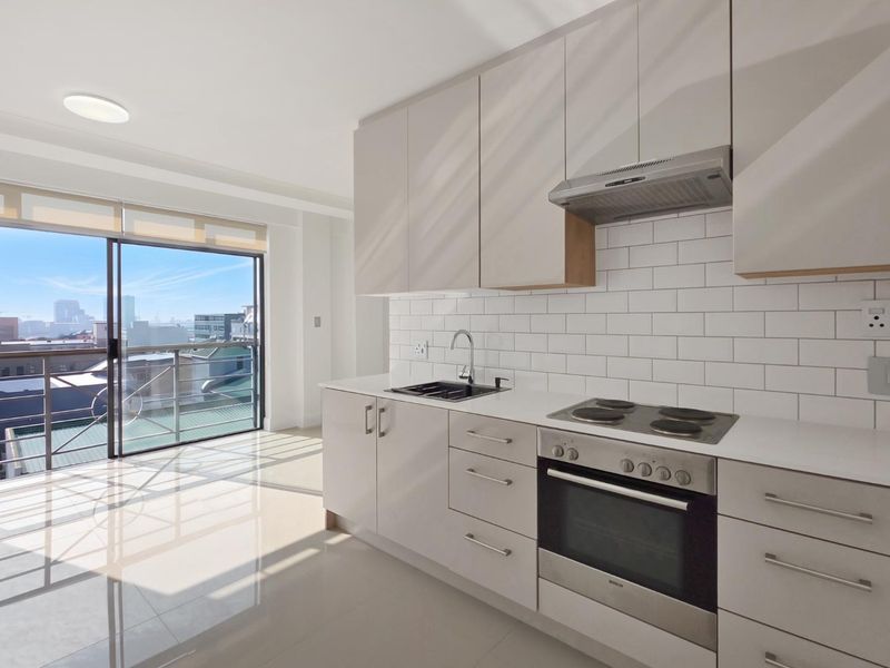 Modern kitchen featuring sleek cabinetry, subway tile backsplash, built-in appliances, and large sliding doors leading to a balcony with city views.