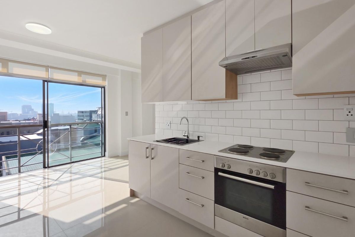 Modern kitchen featuring sleek cabinetry, subway tile backsplash, built-in appliances, and large sliding doors leading to a balcony with city views.