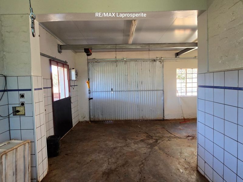 A functional garage space featuring concrete flooring, tiled wall accents, and a large sliding metal door, suitable for vehicle storage or workshop use.