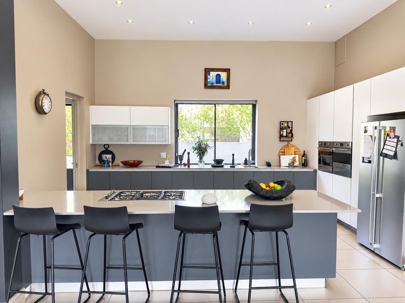 Modern kitchen featuring a large central island with gas cooktop, stone countertops, built-in double ovens, and ample cabinetry with recessed lighting.