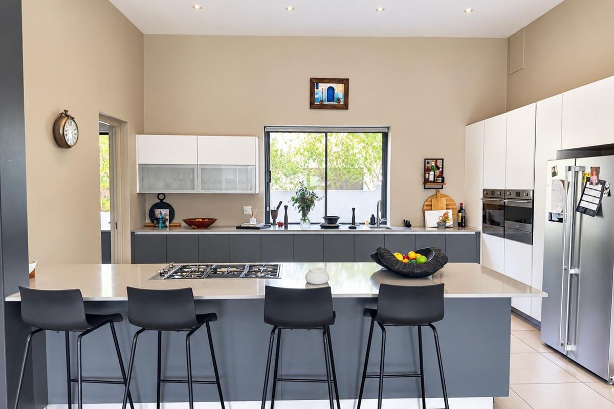 Modern kitchen featuring a large central island with gas cooktop, stone countertops, built-in double ovens, and ample cabinetry with recessed lighting.