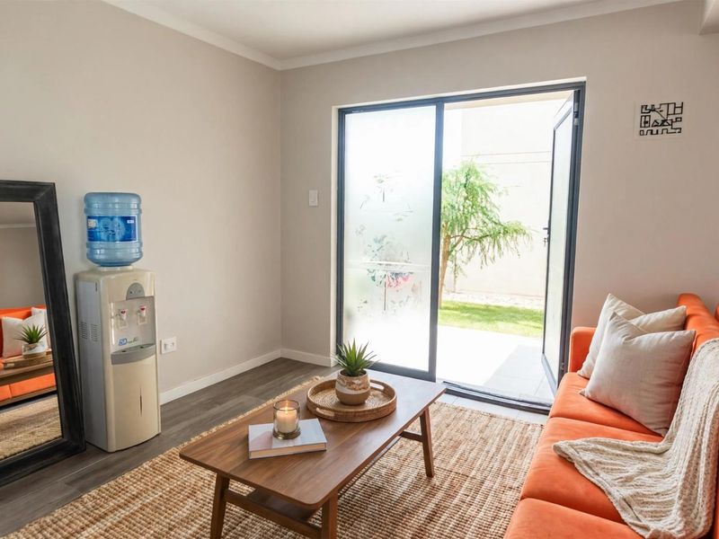 A bright living room featuring modern laminate flooring and a sliding glass door providing direct access to the outdoor garden area.