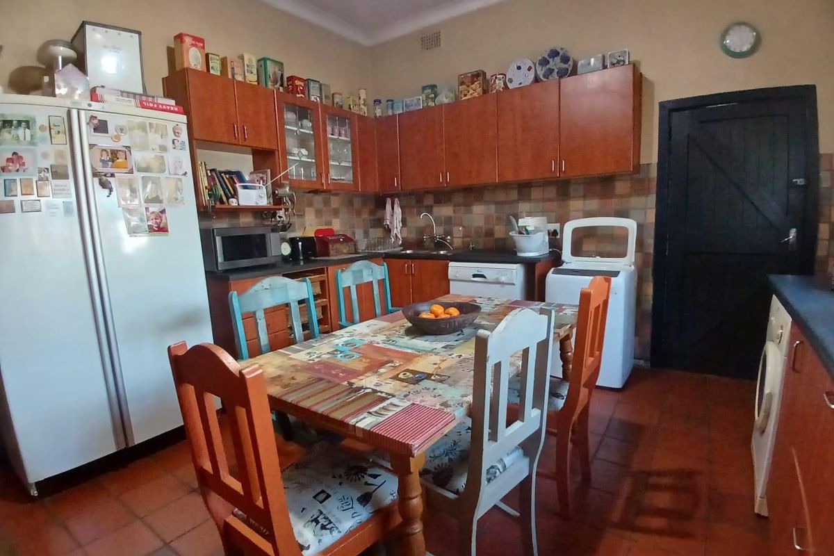 A functional kitchen featuring wooden cabinetry, tiled backsplash, and terracotta floor tiles, providing a practical space for cooking and casual dining.