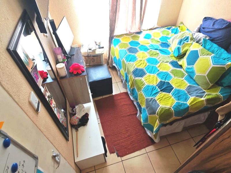 A compact bedroom featuring tiled flooring and a standard door, providing a functional sleeping space.