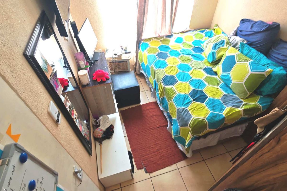 A compact bedroom featuring tiled flooring and a standard door, providing a functional sleeping space.