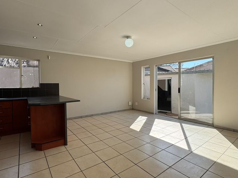 Spacious open-plan living and kitchen area featuring tiled flooring, built-in cabinetry, and direct access to the exterior through a sliding glass door.