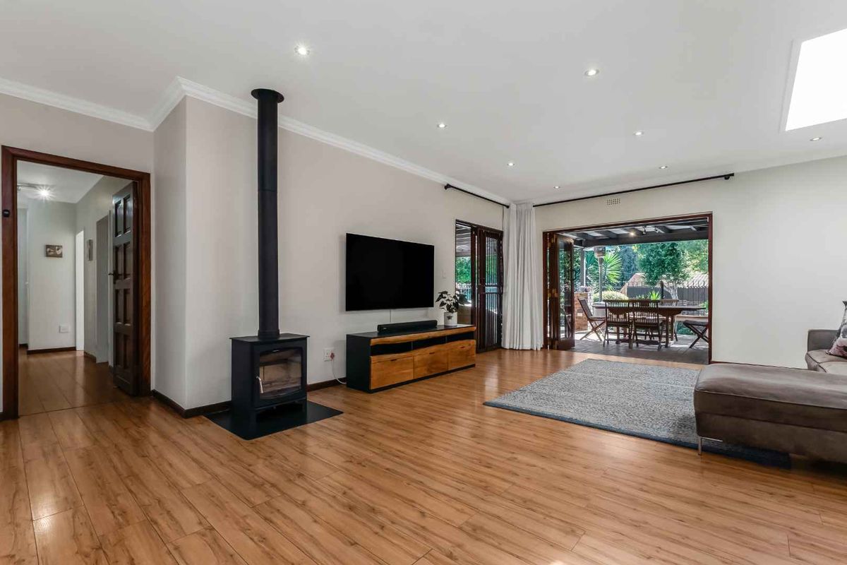 Spacious living room featuring laminate flooring, a modern freestanding fireplace, and large bi-fold doors opening onto an outdoor patio area.