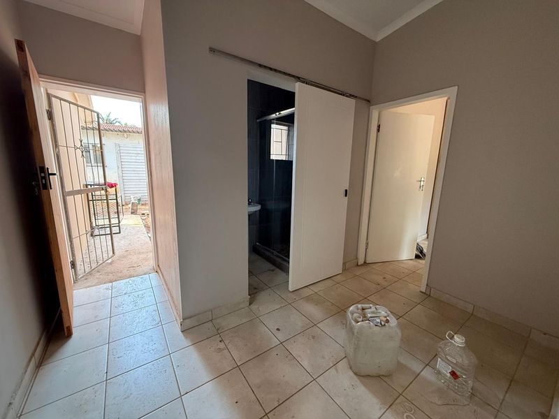 A functional hallway area featuring tiled flooring, a sliding door leading to a bathroom, and an external security gate access.