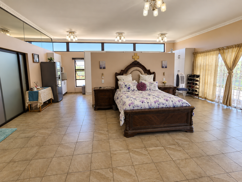 Spacious bedroom featuring tiled flooring, built-in cabinetry, and large windows with natural light, offering a versatile layout with integrated storage solutions.