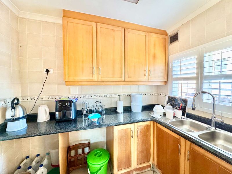 A functional kitchen featuring wooden cabinetry, granite countertops, and a double basin stainless steel sink with tiled backsplash.