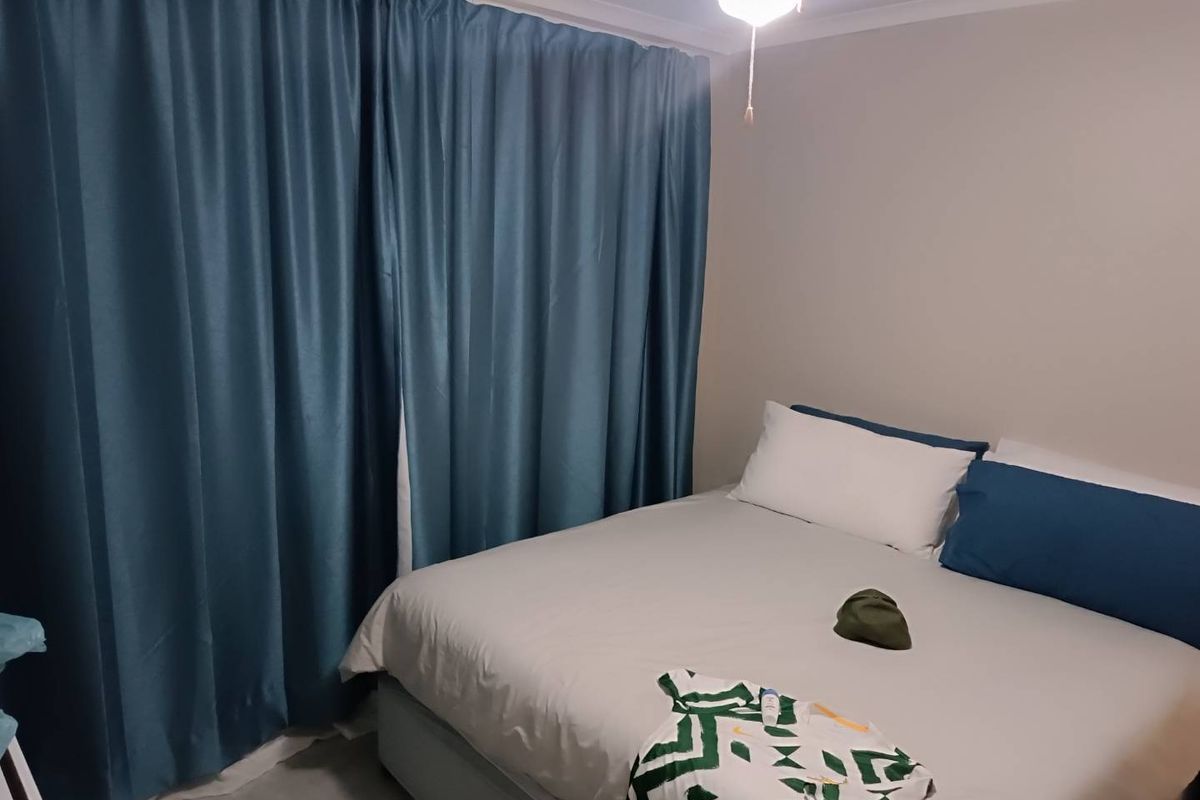 A standard bedroom featuring a ceiling fan and floor-to-ceiling curtains.