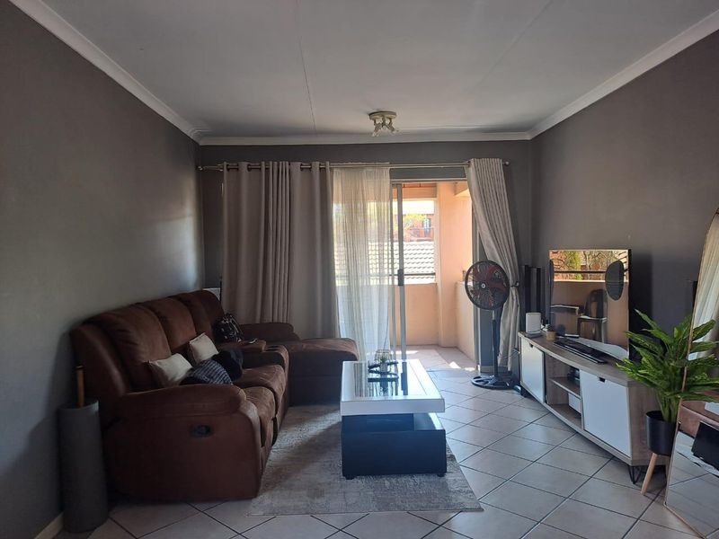 A comfortable living room featuring tiled flooring and a sliding glass door that provides access to an outdoor balcony area.