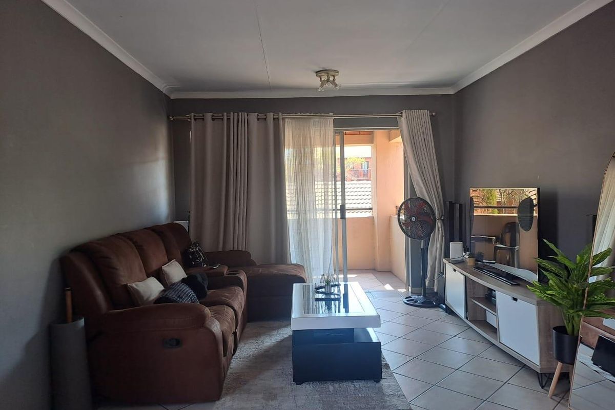 A comfortable living room featuring tiled flooring and a sliding glass door that provides access to an outdoor balcony area.