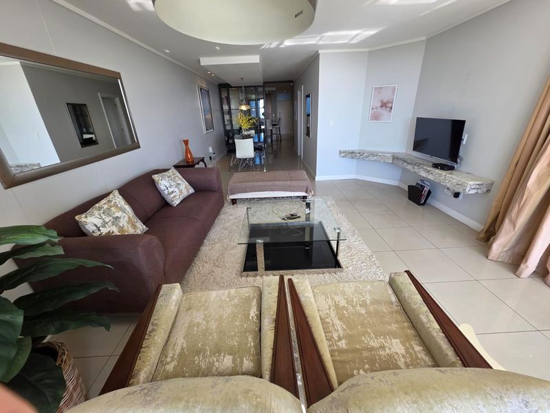 Spacious open-plan living area featuring neutral tiled flooring, recessed lighting, and a custom floating stone shelf for media storage.