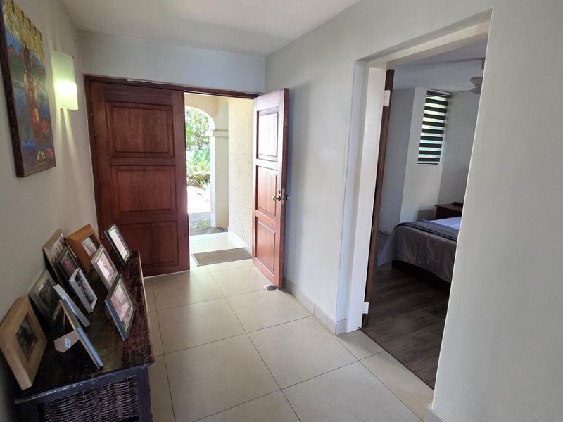 A bright entrance hall featuring tiled flooring and a solid wooden front door, providing direct access to the interior living spaces.