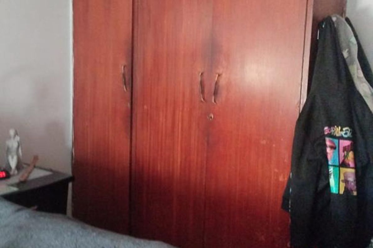 A bedroom featuring a large, full-height built-in wooden wardrobe with overhead storage compartments.