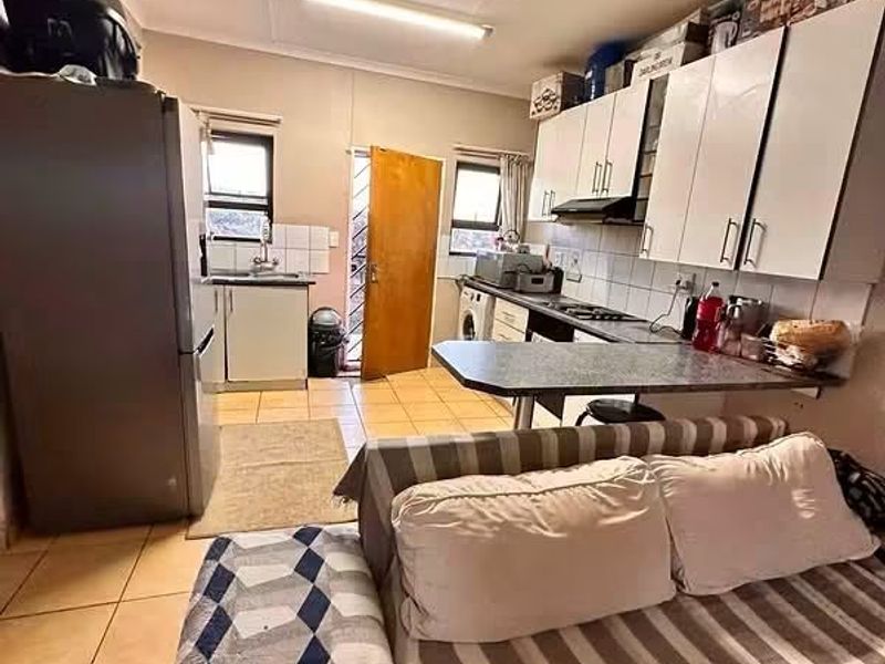 Open-plan kitchen and living area featuring built-in cabinetry, a breakfast bar, and tiled flooring with direct access to an exterior door.